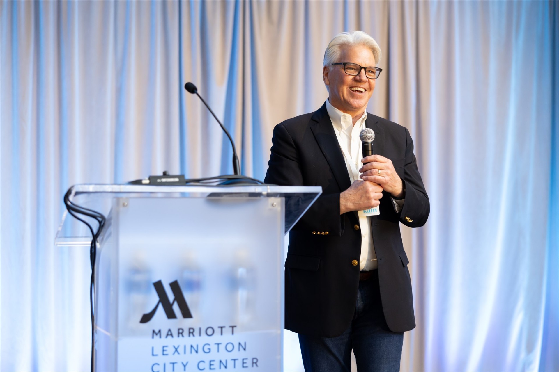 David Kain speaking on stage with a microphone